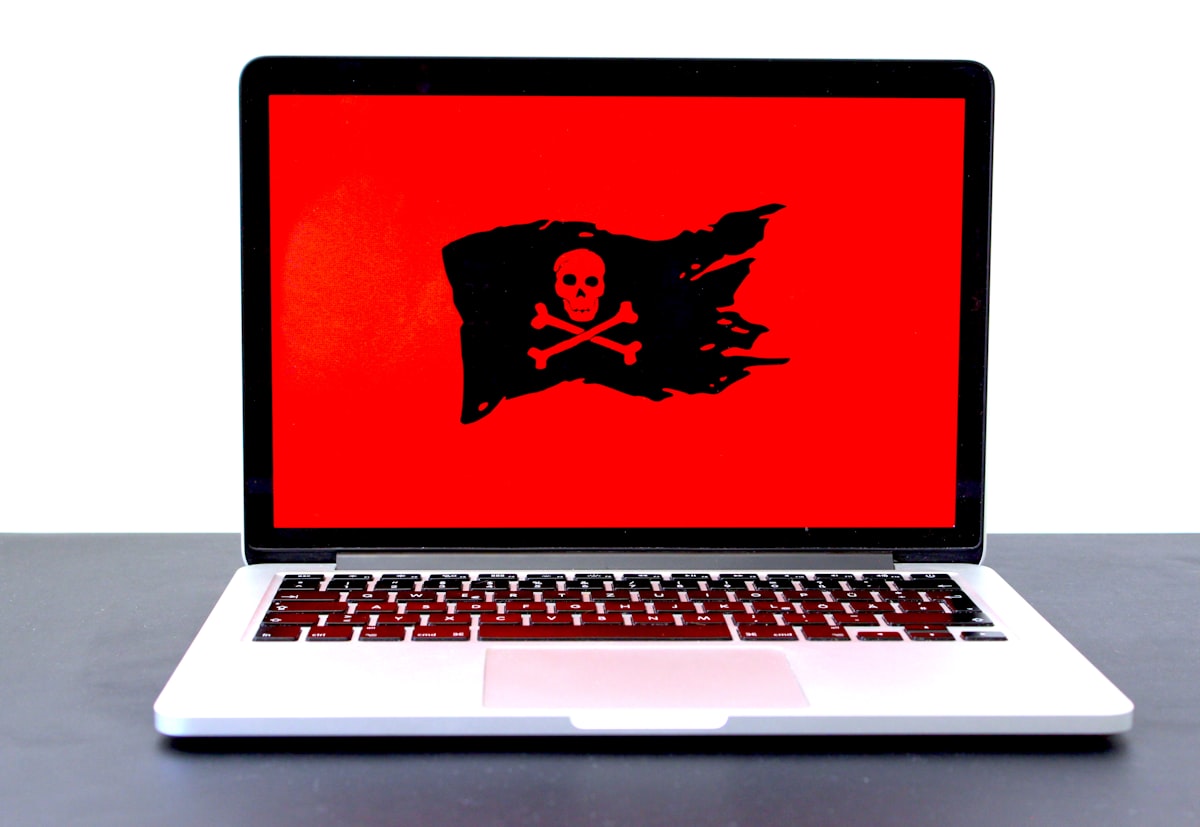 MacBook displaying a pirate flag on a red screen — a visual representation of ransomware locking a small business out of its own systems